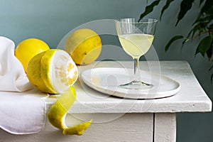 Italian liqueur limoncello in crystal glasses and ripe lemons on a wooden table.