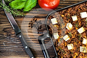 Italian macaroni bake with minced meat and feta cheese on a rustic wooden board photographed from above