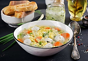 Italian meatball soup and Stelline gluten free pasta in bowl on black table.