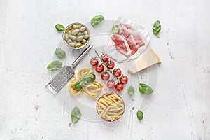 Italian or mediterranean food cuisine and ingredients on white concrete table. Tagliatelle pene pasta olives olive oil tomatoes photo