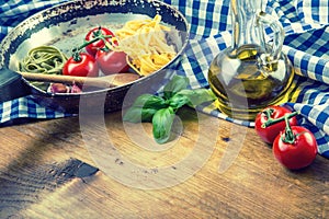 Italian and Mediterranean food ingredients on wooden background.Cherry tomatoes pasta, basil leaves and carafe with olive oil. photo