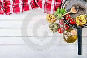 Italian and Mediterranean food ingredients on wooden background.Cherry tomatoes pasta, basil leaves and carafe with olive oil.