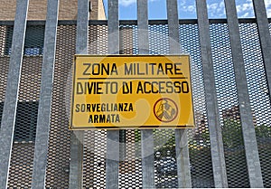 Italian military area with yellow sign: `Military zone, no entry, armed surveillance`. photo