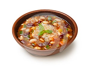 Italian minestrone soup in a brown tarracotta soup bowl isolated on a white background.