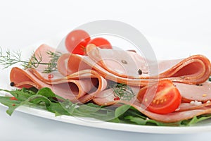 Italian mortadella on white plate with tomato