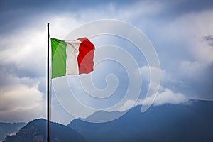 Italian national flag against backdrop of sky and hills