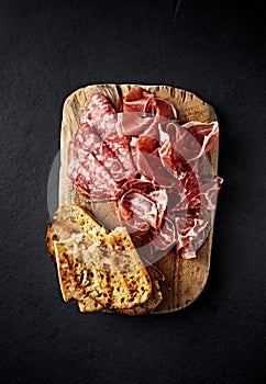 Italian Parma Ham, Coppa and Salami with bread toasts on wooden chopping boardpasto. Top view