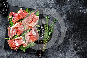 Italian parma prosciutto crudo dried ham on a marble board. Black background. Top view. Copy space