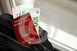 Italian passport and euro money bills with airline tickets on backpack