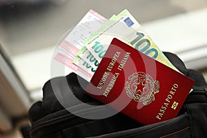 Italian passport and euro money bills with airline tickets on backpack