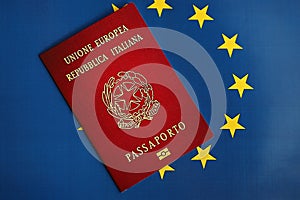 Italian passport of European Union on blue flag background close up. Tourism and citizenship