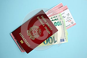 Italian passport with money and airline tickets on blue background close up