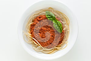 Italian pasta bolognese with basil leaf served in a white bowl top view on a white background. Spaghetti with meat