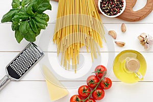 Italian pasta bucatini with tomatoes, basil, oil, garlic and cheese on white wooden table.