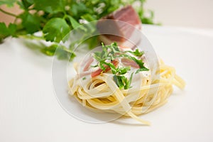 Italian pasta carbonara with ham, basil and egg on a light grey background
