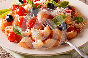 Italian pasta Conchiglie with tomatoes, olives and parmesan clos
