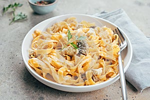 Italian pasta fettuccine alfredo with chicken, mushrooms and sause on plate on stone table. Closeup