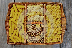 Italian pasta maccheroni, farfalle, spaghetti in a wooden box