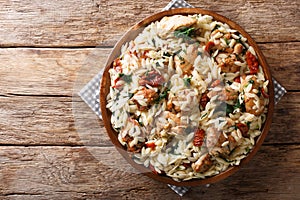 Italian pasta orzo with grilled chicken, dried tomatoes, spinach and cheese close-up. horizontal top view