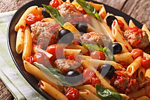 Italian pasta penne with meatballs, olives and tomato sauce closeup. horizontal