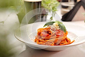 Italian pasta, pomodoro, bolognese. Tomato spaghetti with basil and cheese on a white plate, selective focus.