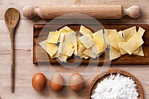 Italian pasta. Rolling pin, flour, eggs, ladle. Wooden surface.