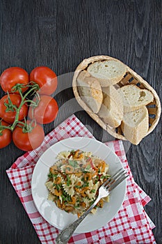 Italian pasta in a sauce with shrimps on a plate, top view. Dark wooden background. Space for text