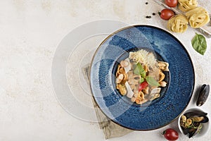 Italian pasta with seafood and fresh basil on a blue plate with a napkin on a light background