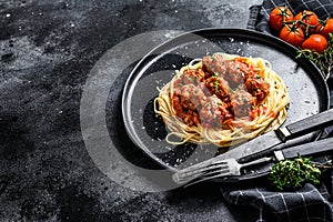 Italian pasta spaghetti with tomato sauce and meatballs. Black background. Top view. Copy space