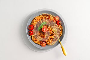 Italian pasta with tomato sauce, cherry tomatoes, mushrooms and basil on a light gray background.