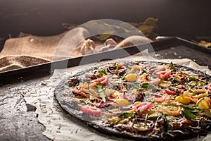 Italian pizza with black dough and seafood on a baking tray from the oven