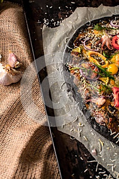 Italian pizza with black dough and seafood on a baking tray from the oven