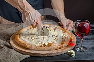 Italian pizza 4 four cheese on the Board with pizza cutter and wine