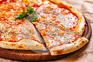 Italian Pizza Margherita with tomatoes and mozzarella cheese on wooden cutting board