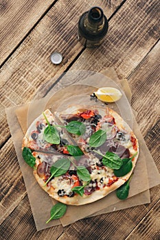 Italian pizza with meat, olives, pepper, spinach, mozzarella wit