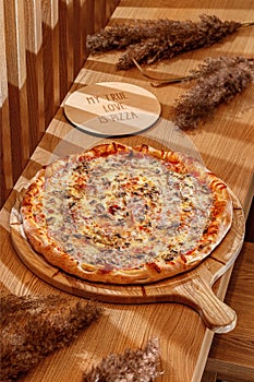 Italian pizza with prosciutto and mushrooms on a traditional wooden plate , Italy.Wooden background, top view