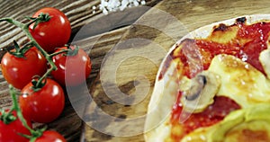 Italian pizza on wooden table with vegetables and spices