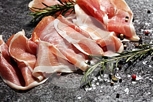 Italian prosciutto crudo or jamon with rosemary. Raw ham with spices photo