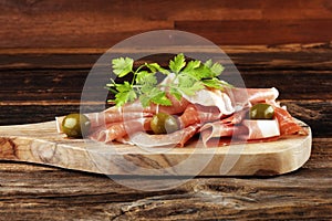 Italian prosciutto crudo or jamon with rosemary. Raw ham appetizer on table