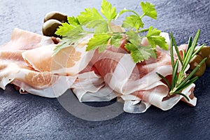 Italian prosciutto crudo or jamon with rosemary. Raw ham appetizer on table