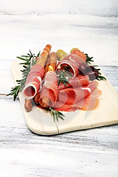 Italian prosciutto crudo or jamon with rosemary. Raw ham appetizer on table