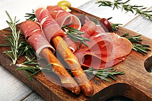 Italian prosciutto crudo or jamon with rosemary. Raw ham appetizer on table