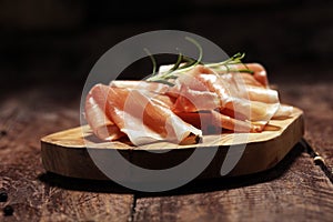 Italian prosciutto crudo or jamon with rosemary. Raw ham on rustic background photo