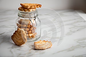 Italian puff pastry fan wavers cookies biscuits with preserving glass jar on marble table background