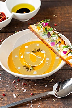 Italian pumpkin soup Zuppa di giornata on white porcelain plate on wooden table photo