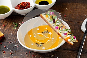 Italian pumpkin soup Zuppa di giornata on white porcelain plate on wooden table