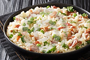 Italian risotto Risi e Bisi made from rice with peas and ham close-up in a plate. horizontal