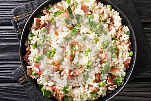 Italian risotto Risi e Bisi made from rice with peas and ham close-up in a plate. horizontal top view