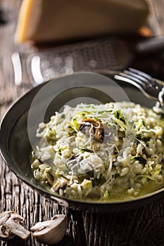 Italian risotto zucchini mushrooms and parmesan in dark plate