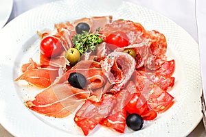 Italian salumi meat platter - prosciutto ham, salami olive and cherry tomato.